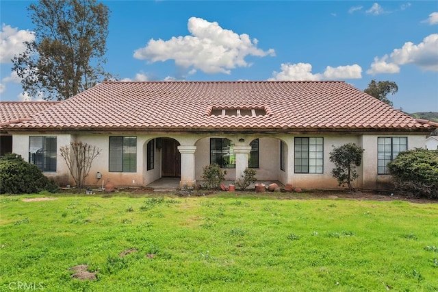 view of front of property featuring stucco siding, a front yard, and a tile roof