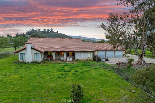 back of property with fence, a tiled roof, stucco siding, and concrete driveway