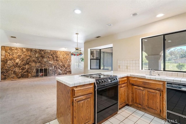 kitchen with brown cabinetry, black appliances, a peninsula, and a sink