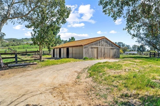 view of pole building featuring fence and a rural view