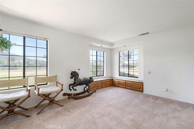 sitting room featuring visible vents and light carpet