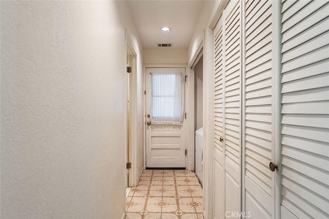 doorway featuring recessed lighting, visible vents, a textured wall, and light floors