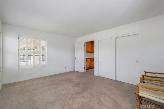unfurnished bedroom with light carpet and a closet