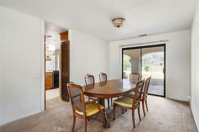 dining room with baseboards, visible vents, and light carpet
