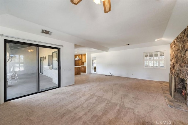 unfurnished living room with a wealth of natural light, visible vents, ceiling fan, and carpet floors