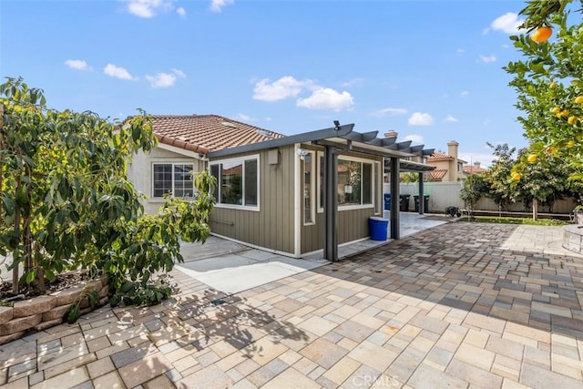 rear view of property featuring a patio area, fence, and a tile roof