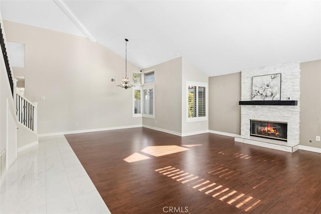 unfurnished living room featuring baseboards, an inviting chandelier, a stone fireplace, wood finished floors, and stairs