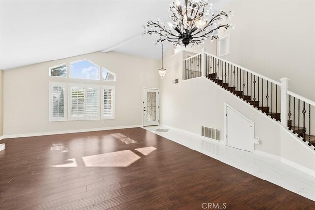 unfurnished living room with an inviting chandelier, stairway, visible vents, beamed ceiling, and wood finished floors