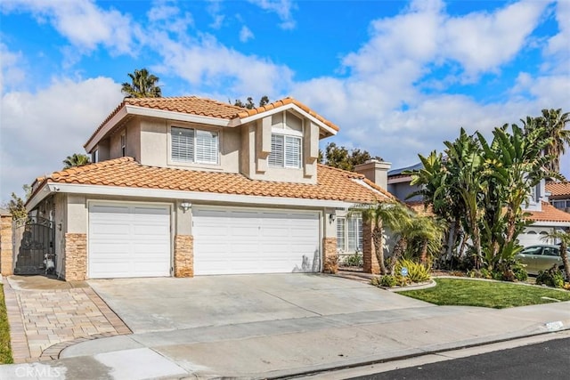 mediterranean / spanish home featuring a garage, driveway, stucco siding, and a tile roof