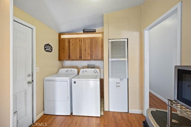 washroom featuring cabinet space, light wood-style flooring, washer and dryer, and baseboards