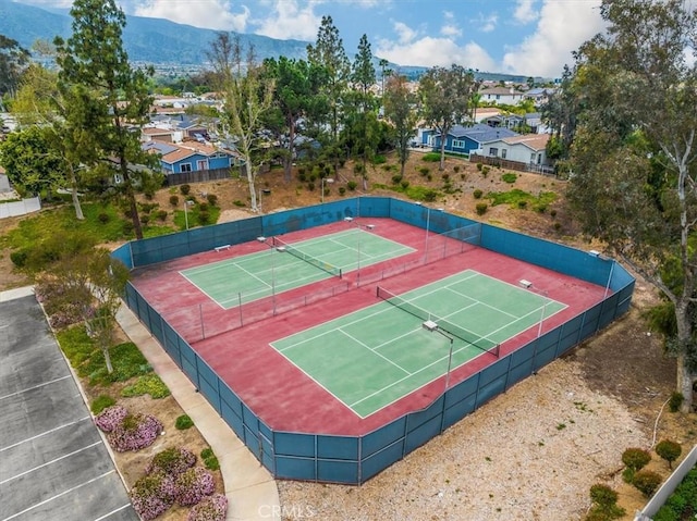 view of sport court with a tennis court, a residential view, fence, and a mountain view