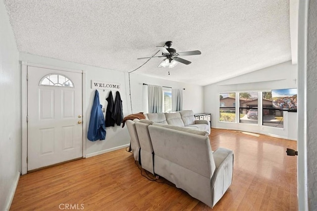 living room with ceiling fan, vaulted ceiling, light wood-style floors, and a textured ceiling
