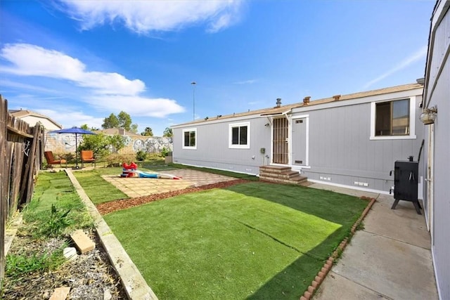 back of house with entry steps, a yard, crawl space, a fenced backyard, and a patio