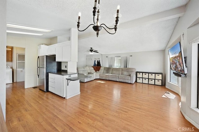 kitchen with ceiling fan with notable chandelier, freestanding refrigerator, lofted ceiling with beams, washer / clothes dryer, and dark countertops