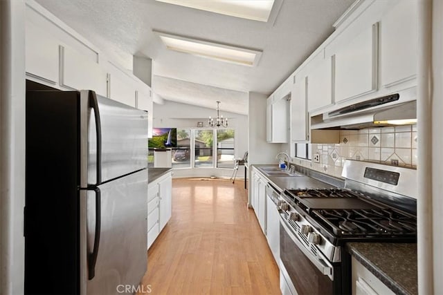 kitchen featuring stainless steel appliances, under cabinet range hood, white cabinetry, and a chandelier