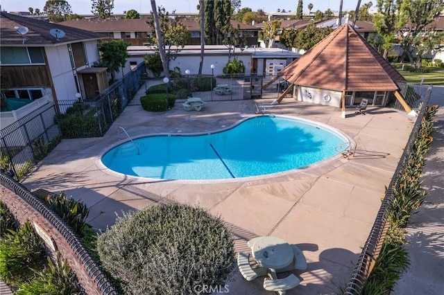 pool featuring a patio area, fence, and an outbuilding