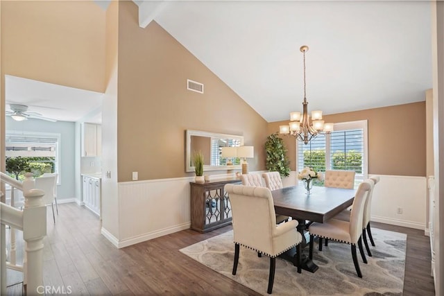 dining area with visible vents, wainscoting, wood finished floors, ceiling fan with notable chandelier, and high vaulted ceiling