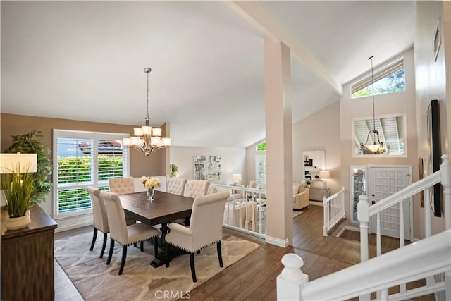 dining space with high vaulted ceiling, a notable chandelier, baseboards, and wood finished floors