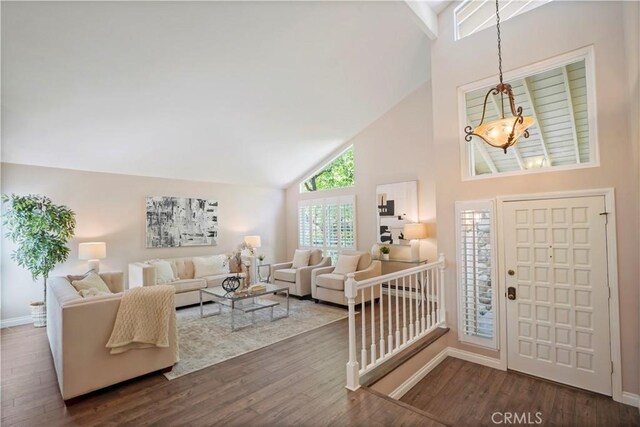 entryway with wood finished floors, high vaulted ceiling, and baseboards