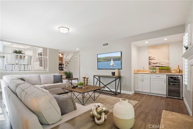 living area with baseboards, indoor wet bar, stairs, dark wood-type flooring, and beverage cooler
