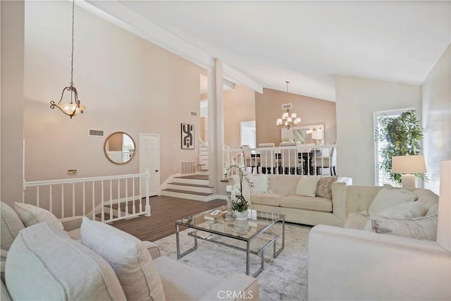 living area featuring an inviting chandelier, beamed ceiling, visible vents, wood finished floors, and baseboards