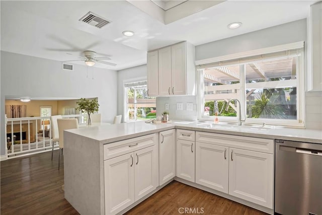 kitchen featuring tasteful backsplash, stainless steel dishwasher, light countertops, and visible vents