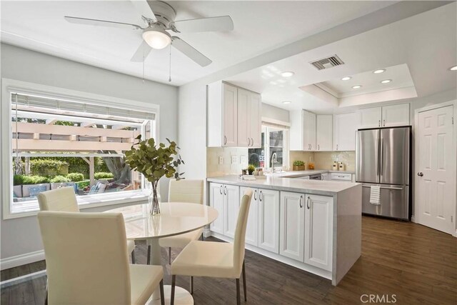 kitchen with freestanding refrigerator, white cabinetry, visible vents, light countertops, and dark wood-style floors