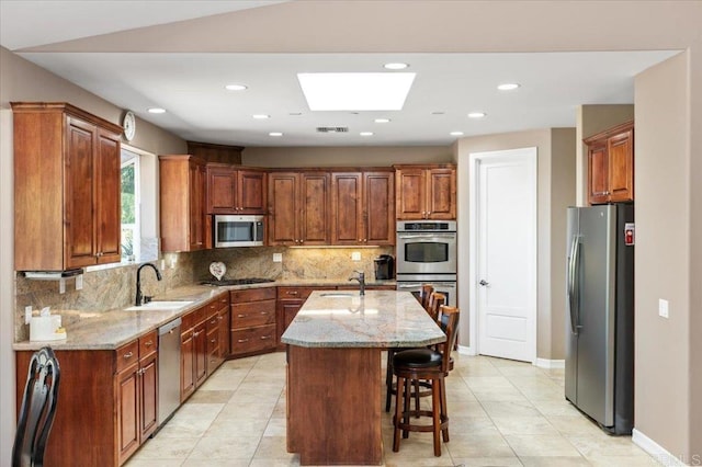 16270 Pauma Valley Dr, Pauma Valley, CA 92061 - kitchen featuring appliances with stainless steel finishes, decorative backsplash, a skylight, light stone counters, and light tile patterned floors