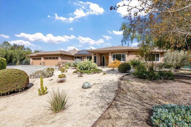 16270 Pauma Valley Dr, Pauma Valley, CA 92061 - ranch-style house featuring an attached garage, concrete driveway, roof mounted solar panels, and stucco siding