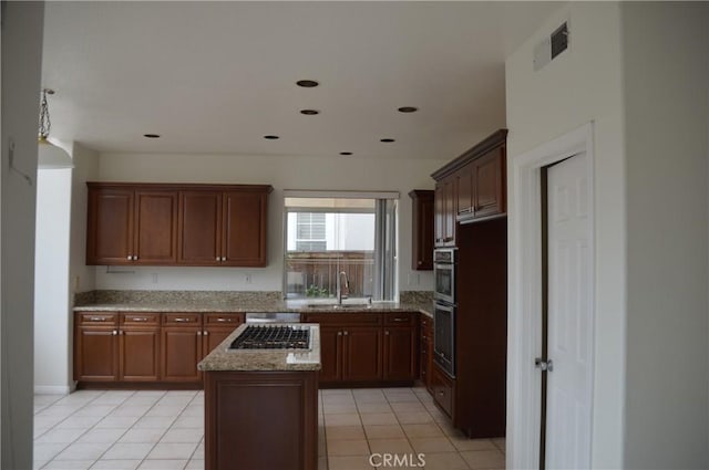 24391 Rue De Gauguin, Laguna Niguel, CA 92677 - kitchen featuring visible vents, a center island, a sink, light stone counters, and light tile patterned flooring