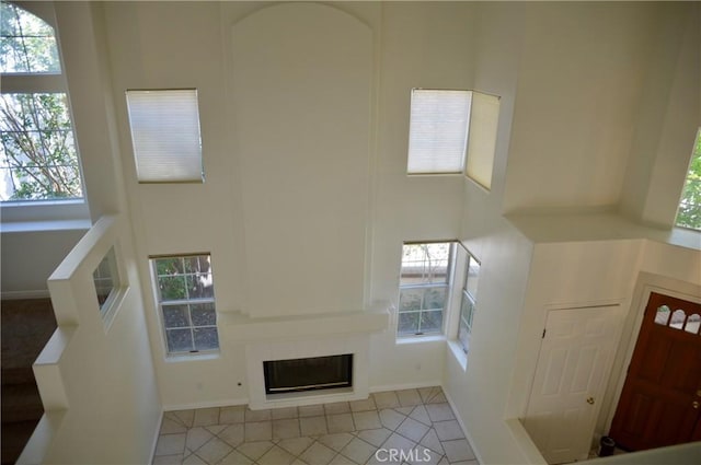 24391 Rue De Gauguin, Laguna Niguel, CA 92677 - unfurnished living room featuring healthy amount of natural light, tile patterned flooring, a glass covered fireplace, and a towering ceiling