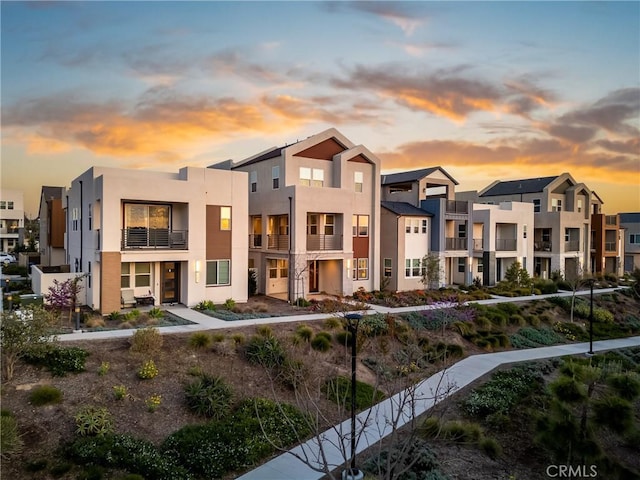 rear view of property with a residential view, a balcony, and stucco siding