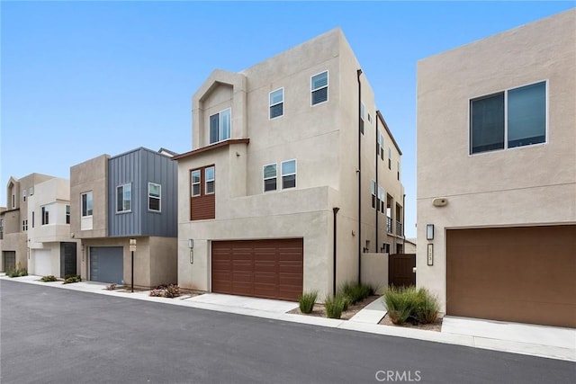 view of front facade featuring an attached garage, a residential view, and stucco siding