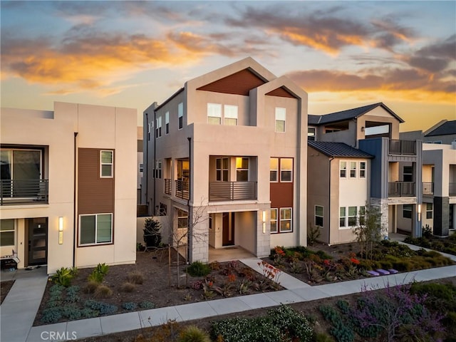 contemporary home with a standing seam roof, stucco siding, metal roof, and a balcony