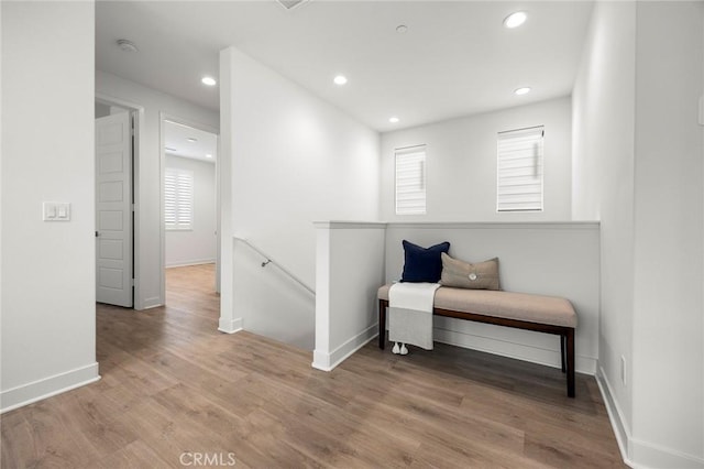 corridor with baseboards, recessed lighting, wood finished floors, and an upstairs landing