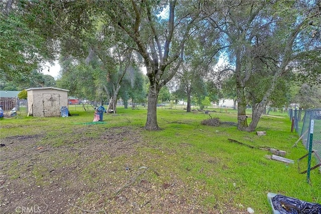 view of yard featuring fence, a storage shed, and an outdoor structure