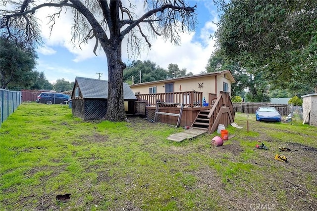 back of house featuring an outbuilding, a fenced backyard, a wooden deck, and a yard