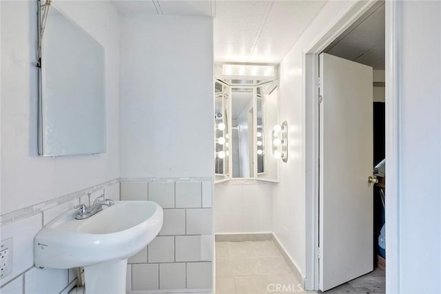 bathroom featuring tile patterned floors, tile walls, and a sink