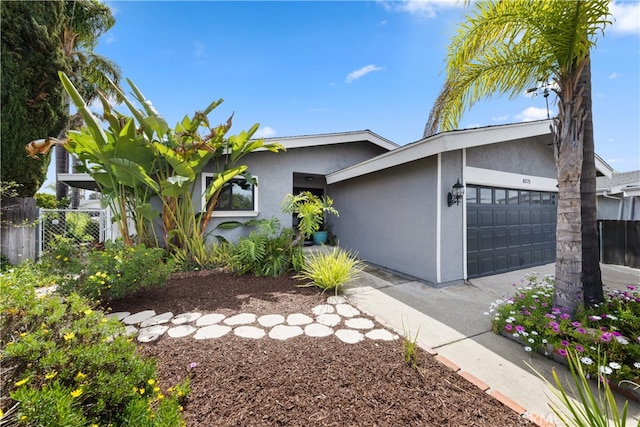 view of front of house featuring stucco siding, a garage, and fence