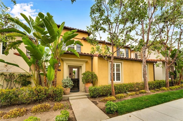 mediterranean / spanish house featuring a tile roof and stucco siding