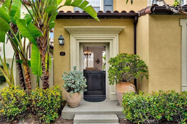 doorway to property featuring a tiled roof and stucco siding