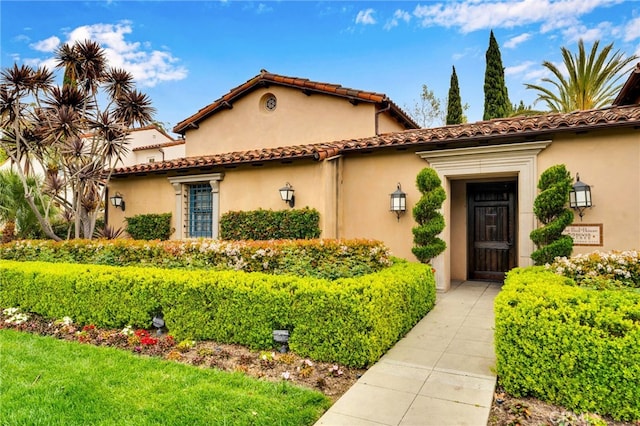 mediterranean / spanish home with stucco siding and a tiled roof