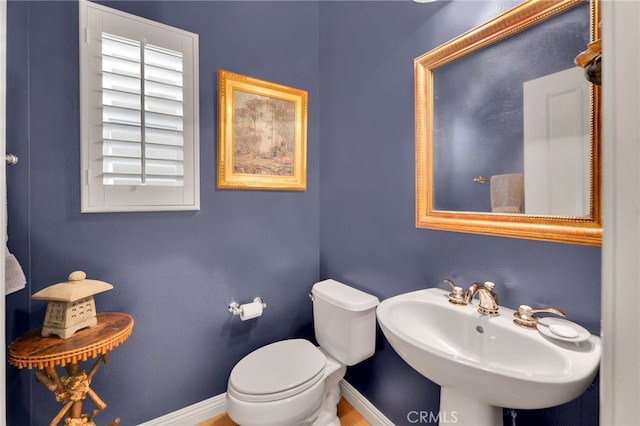 bathroom featuring toilet, a sink, and baseboards