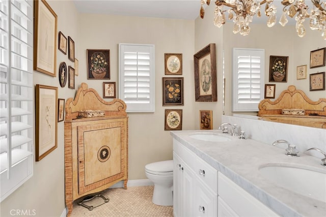 bathroom featuring double vanity, a sink, a chandelier, and toilet