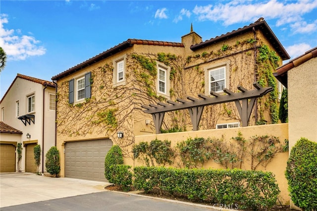mediterranean / spanish-style house with driveway, stucco siding, a tile roof, and an attached garage