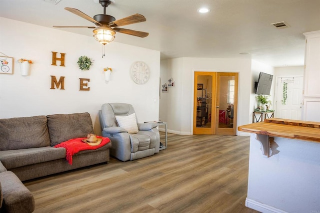 living room featuring recessed lighting, wood finished floors, visible vents, a ceiling fan, and baseboards