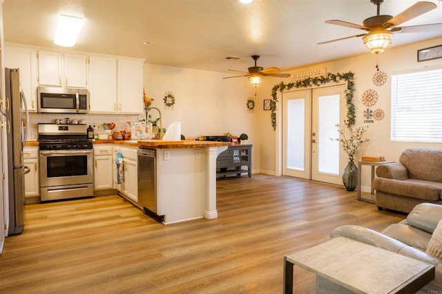 kitchen with a ceiling fan, open floor plan, french doors, a peninsula, and appliances with stainless steel finishes