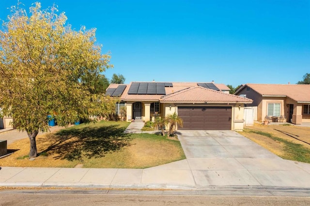 view of front of property with a tiled roof, solar panels, concrete driveway, an attached garage, and stucco siding