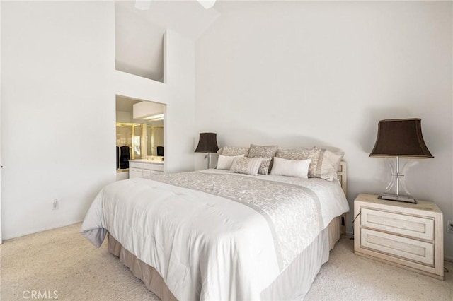bedroom featuring high vaulted ceiling, ensuite bathroom, and light colored carpet