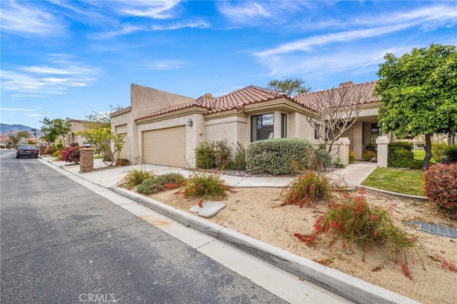 mediterranean / spanish-style home with a tiled roof, stucco siding, driveway, and a garage